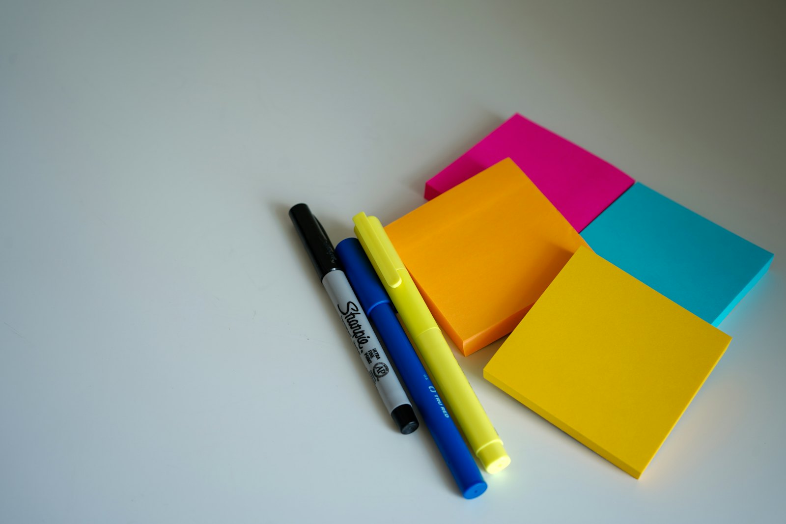 A pen resting beside orange sticky notes