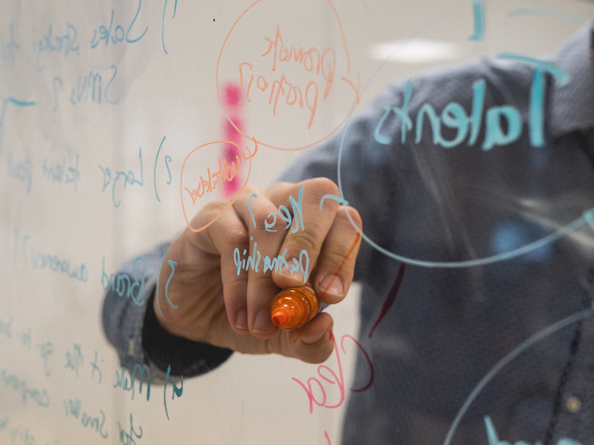 A designer drawing diagrams on a glass whiteboard