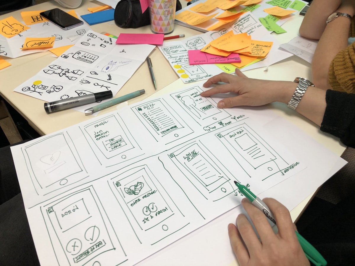 Hands sketching interface layouts on paper