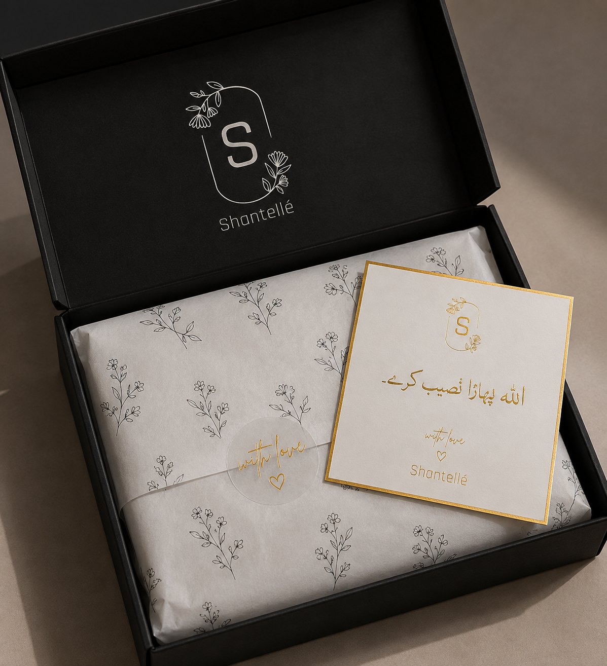 The box opened, floral tissue and a gold-bordered note card inside